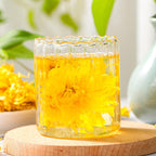 Loose golden chrysanthemum blooming tea leaves in a clear glass teapot, showcasing vibrant yellow blossoms and delicate tea leaves.