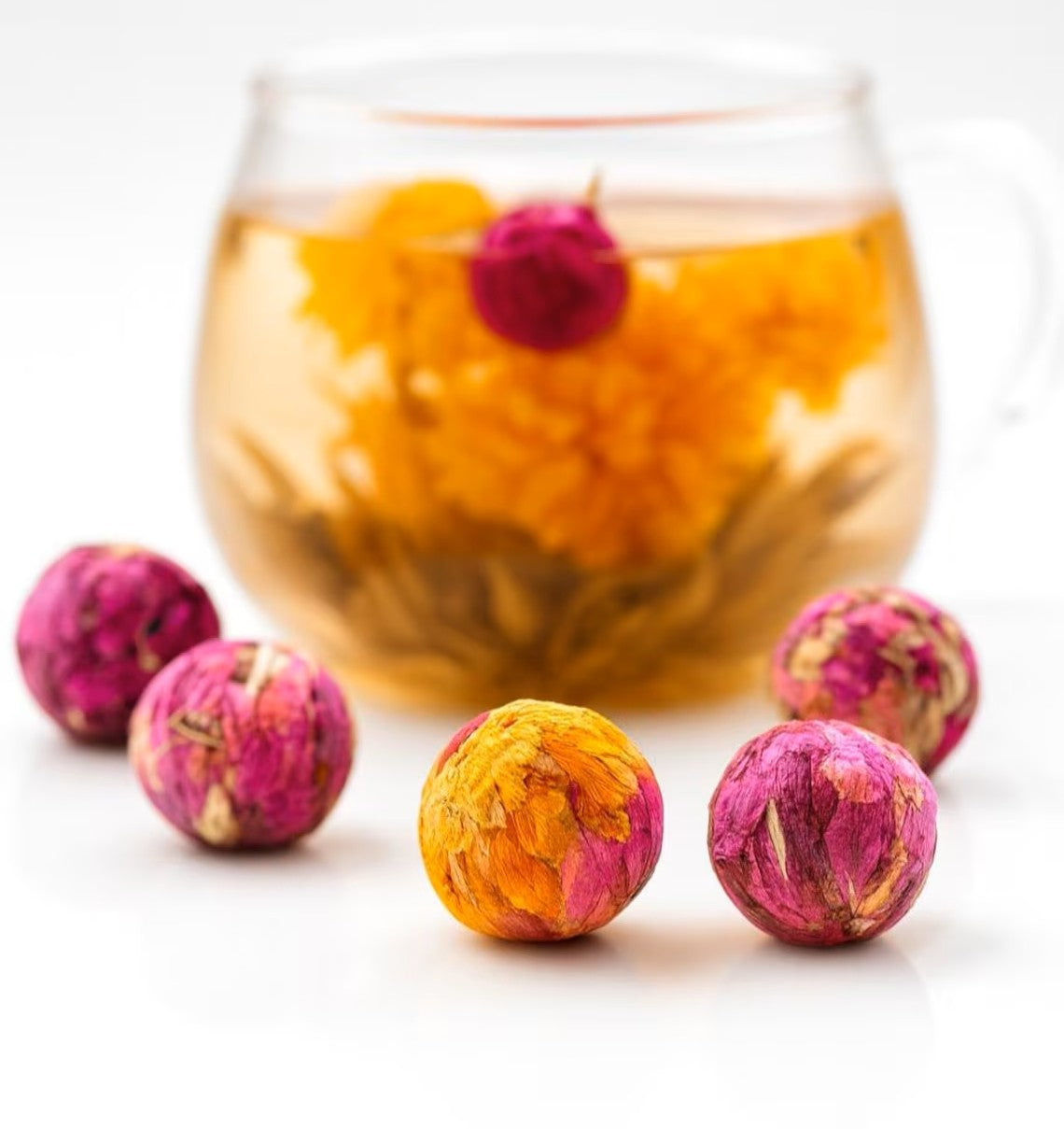 Queen Tee's Organic Dried Rose Blooming Tea Ball showing a natural herbal loose tea with blooming rose flowers and tea bombs.