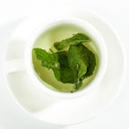 Loose peppermint leaf herbal tea from Queen Tee's Herbal Teas, showing fresh green peppermint leaves in a natural setting.